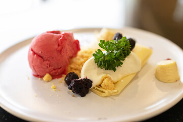 Soft crape with sorbet ice cream with berry juicy sauce and banana sliced with crumble.