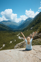 a girl sits on the edge of a cliff and looks into the distance, in the distance there is a river and a gorge, a good mood, clouds and a mountain landscape