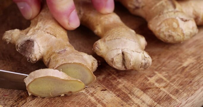Sliced pieces of ginger root on the table, cooking a dish using ginger root which is cut with a knife