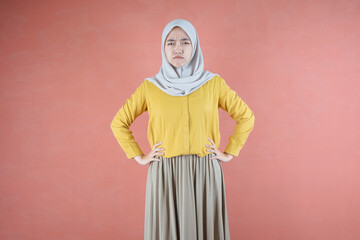 Fototapeta na wymiar Beautiful Asian woman in yellow shirt and hijab hands on waist on brown background