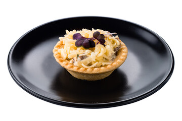 Tartlet with cheese, mushrooms, sauce and microgreens on plate.