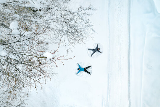 People mKing snow angels by forest