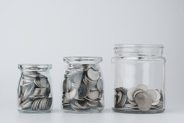 Three different size of glass jars with coins on white background. Save money concept for Finance Banking Business Ideas, Investments, Funds, Bonds, Dividends and Interest.