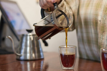 cook pours tea into teapot cup, close-up, black tea on table, blurred background