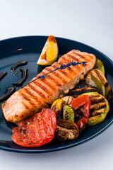 Grilled salmon fish fillet with zucchini, sweet pepper, mushrooms tomatoes and sauce.