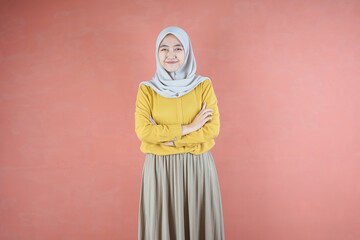  Beautiful Asian woman in yellow shirt and hijab smiling cheerfully on brown background