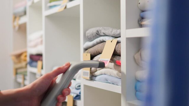 Fashionable clothes, Stylish woman Confidently scans a barcode with a scanner. Hanger with clothes, In slow motion Sales assistant Going through hangers with clothes in a warehouse, climate change
