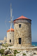 Stone windmills in clear weather in spring, Mandraki port of Rhodes, Greece.