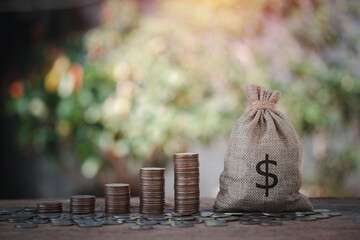 Money bag and stacking money with silver coins scattered on wooden table, plan investment for the...