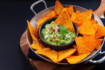 Party food concept Homemade Guacamole and Tortilla chips on black background with copy space