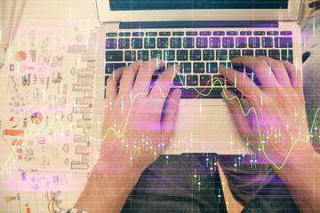 Double exposure of man's hands typing over laptop keyboard and forex chart hologram drawing. Top view. Financial markets concept.