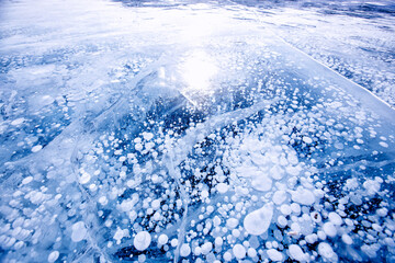 Gas methane bubbles frozen in winter ice of lake Baikal, abstract background