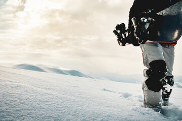 Snowboarder dressed in a full protective gear for extreme freeride snowboarding posing with a snowboard walking. Isolated on gray white snow background.