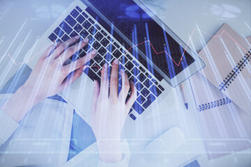 Double exposure of woman hands working on computer and forex graph hologram drawing. Top View. Financial analysis concept.