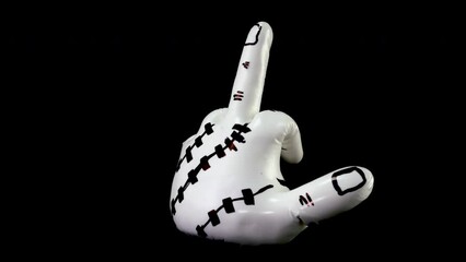 White sculpture in shape of hand showing obscene gesture rotates against black background. Object of modern abstract art. Close-up.