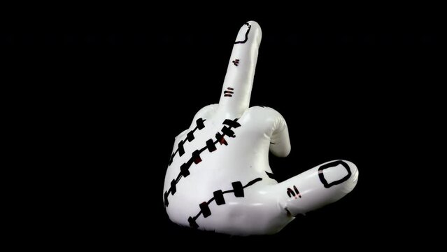 White sculpture in shape of hand showing obscene gesture rotates against black background. Object of modern abstract art. Close-up.