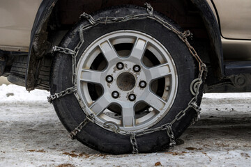 Wheel Car with winter chains for snow and ice road . Snow chains on tire. The wheel of a car with...