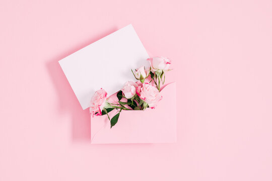Top View On Open Pink Envelope With Paper Card, Bouquet Of Pink Flowers Rose On Pastel Pink Table Background. Birthday, Wedding, Mother's Day, Valentine's Day, Women's Day. Flat Lay, Copy Space