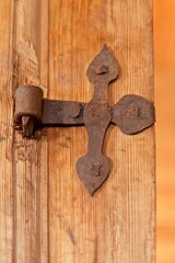 Closeup of a old rusty door hinge on wooden weathered door.