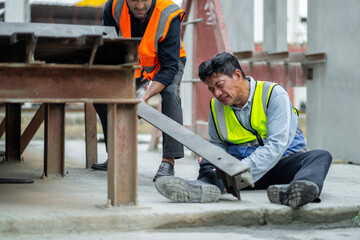 An engineer has an accident where steel falls on his leg at work, causing serious leg injuries. and get help from colleagues in the area under construction industrial factory, concept, safe work