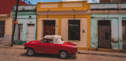 The charming oldtimer shines against the vibrant colors of Cuba's homes