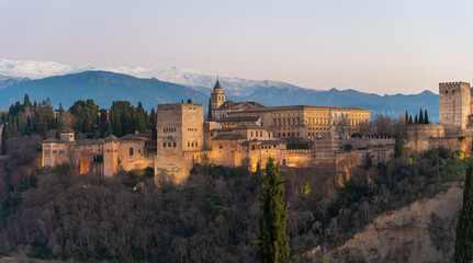 Fototapeta na wymiar Alhambra historical monument at sunset with Sierra Nevada and its snowy mountains in the background. Photo taken from San Nicolas viewpoint in Granada, Andalusia, Spain