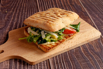 Grilled sandwich with green salad and Parmesan on a wooden serving board