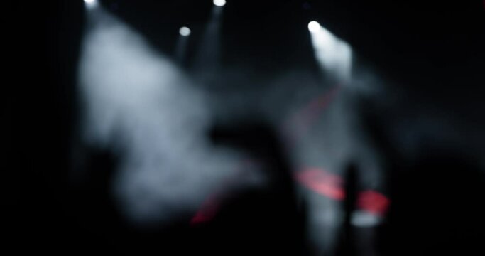 Abstract silhouette people in a crowd with hands up dancing and holding smart phones. Flashes of lights and lasers..