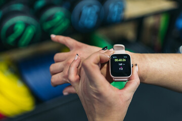 Close-up cropped image of a sporty young woman in the gym activating her digital watch to count the exercise done.