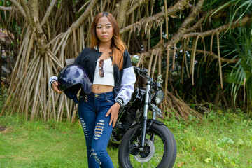 Beautiful brunette woman posing on motorbike, wears stylish tight jeans