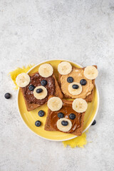 Fototapeta na wymiar Breakfast toasts with nut butter, banana and blueberry with cute funny animal face. Kids food, breakfast for kids or school lunch. Top view