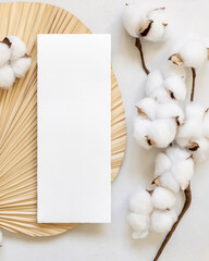 Blank card on dried palm leaf with cotton flowers top view, wedding mockup