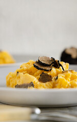 Scrambled eggs with fresh black truffles from Italy served in a plate close up, gourmet breakfast