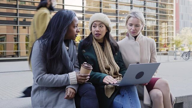 Group of business only woman discussing work using laptop outdoors. Asian lady explain new project to Multiracial people. High quality 4k footage