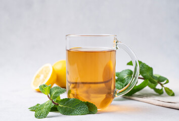 Aroma a glass of lemon tea with mint on a light background close up. The concept of a healthy breakfast drink for immunity and vigor