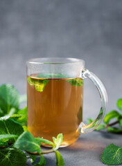 Aroma a glass of herbal tea with mint on a dark background close up. The concept of a healthy breakfast drink for immunity and vigor.