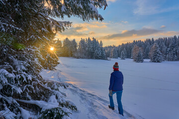 nice and active senior woman snowshoeing in deep powder snow during sunset in the mountains of the Bregenz Forest  Alps near Sulzberg, Vorarlberg, Austria
