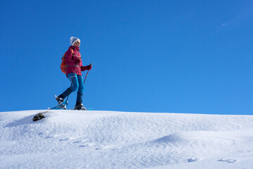 nice and active senior woman snowshoeing in deep powder snow in themountains of the Allgau alps near Balderschwang, Bavaria, Germany

