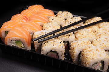 Sushi set to go in a plastic container with chopsticks close-up