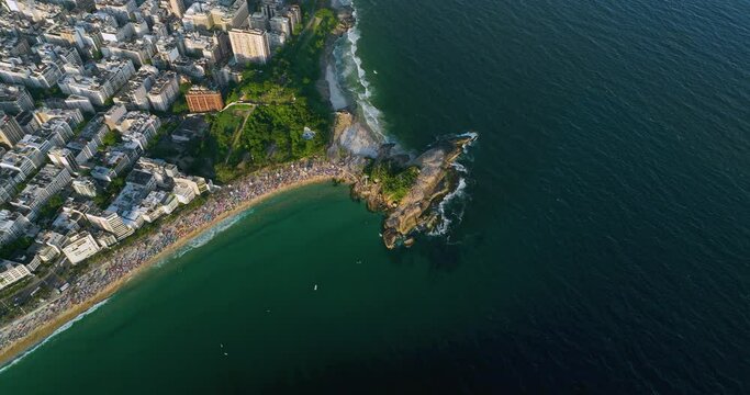 People watching sunset on small Arpoador peninsula between Ipanema and Copacabana Beach, Rio De Janeiro, Brazil. aerial high angle view