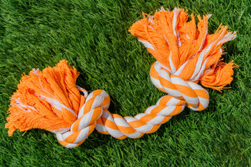 Orange gray rope dog toy on synthetic grass hard light