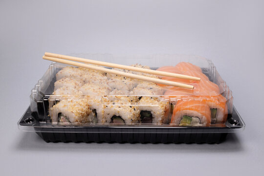 Set Of Sushi To Go In A Plastic Container On A Gray Background, Japanese Cuisine. Copy Space For Text