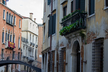 Fototapeta na wymiar A captivating snapshot of Venice with an ornate metal bridge crossing over a canal, surrounded by classical Venetian architecture and lush balcony greenery.