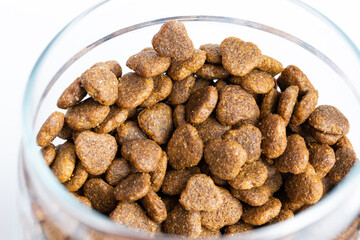 Dry pet food in a jar close-up on a white background.on a gray background
