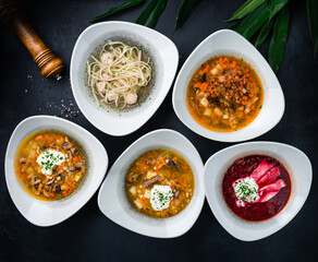 Set of soups from the restaurant menu: cucumber soup, mushroom soup, beetroot soup (borscht), soup with noodles and pork meatballs.