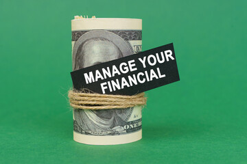 On a green surface, rolled dollars with a black sign that says - Manage your financial