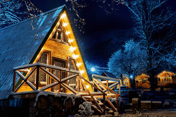 Triangular wooden house illuminated at winter night