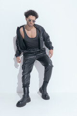 muscle young man in leather suit with sunglasses looking down