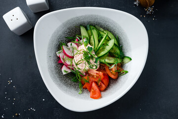 Green salad with cucumbers, tomatoes, radish, greens and sauce.