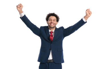 excited young businessman with curly hair holding fists in the air